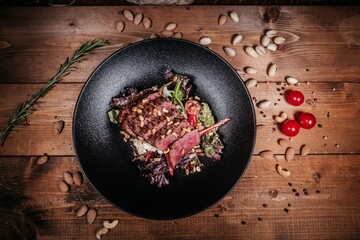 Textured Still Life: Warm Salad with Roast Beef, Pine Nuts and Vegetables Placed on Black Plate...