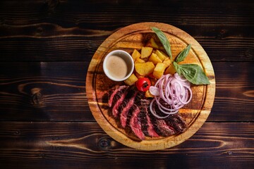 Exquisite Steak with Roasted Potatoes and Red Onion on Wooden Board, with Sauce and Basil, Top View, for Restaurant Menu and Culinary Advertising.