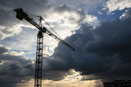 a lone construction crane against a dramatic cloudy sky, concept of ambition and progress