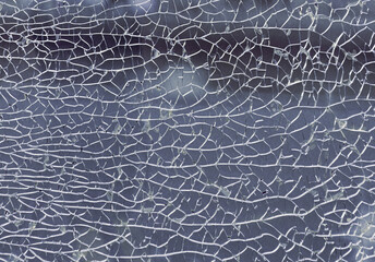 Detail of broken tempered glass pane too many small irregular shape pieces holding together. Texture of cracked broken glass cracked by impact, Cracks on the glass surface background, Copy space.