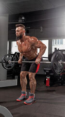 fit individual engages in strength training workout executing bent over barbell rows. gym features...