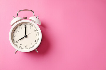 White alarm clock on pink background, top view. Space for text
