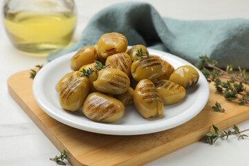 Delicious grilled green olives on white table, closeup