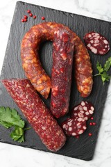 Different smoked sausages, parsley and peppercorns on white marble table, top view