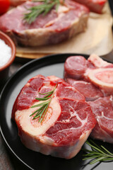 Pieces of raw beef and rosemary on wooden table, closeup