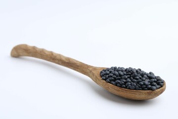 Raw lentils in wooden spoon isolated on white