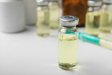 Hepatitis vaccine in glass vials and syringe on white table, closeup. Space for text