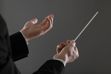 Conductor with baton on grey background, closeup