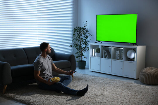 Man watching TV set with green screen in room. Chroma key compositing
