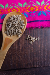 A spoonful of sunflower seeds is on a wooden table.