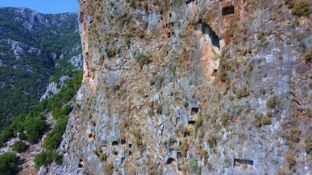 Remains of an ancient Lycian rock necropolis in the city of Pinara in Turkey. A rock with carved tombs. Lycian rock tombs overlooking the ancient Lycian city of Pinara from the air. Drone. 4К
