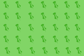 Colorful arrangement of green push pins on a bright green background creating a vibrant pattern