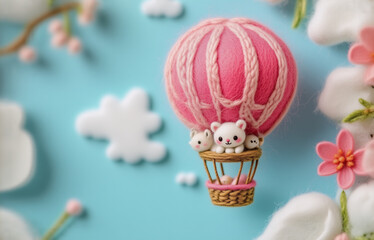 Adorable pink yarn hot air balloon, carrying tiny felted animals, floats amidst delicate sculpted flowers and clouds on a light blue background.  A charming miniature scene.