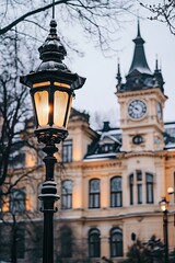 Obraz premium A picturesque winter scene featuring a vintage street lamp in the foreground. with a historic clock tower and snow-covered buildings in the background. evoking a serene atmosphere