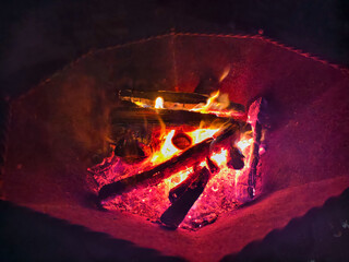 Night photo of a bonfire in an iron fire bowl. Photography of flame of burning wood on black...