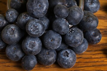 Close up of a pile of scattered blueberries on a wood table.