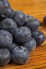 Close up of a pile of scattered blueberries on a wood table.