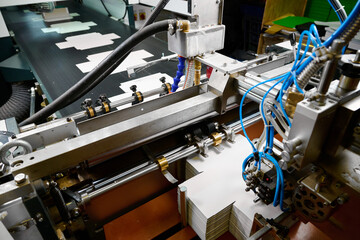 Mechanism for feeding paper sheets in a glue-spreading machine during a busy manufacturing day
