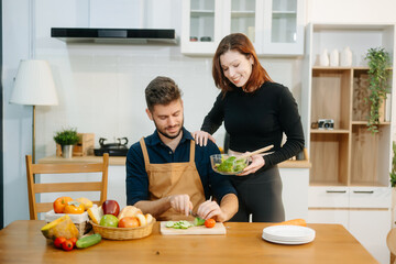 Discover a joyful couple preparing fresh vegetables, embracing healthy eating and teamwork in a...