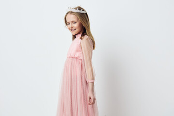 A joyful young girl wearing a pink tulle dress and a crown, showcasing happiness and innocence...