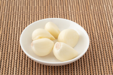 小皿に載せた皮をむいたニンニク