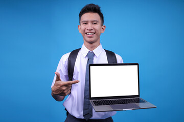 Joyful Indonesian Guy In High School Student Wear Pointing An Open Laptop With Mockup Space