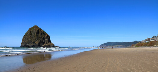 Panoramic view of the iconic Haystack Rock and Cannon Beach in Oregon on a clear sunny day.