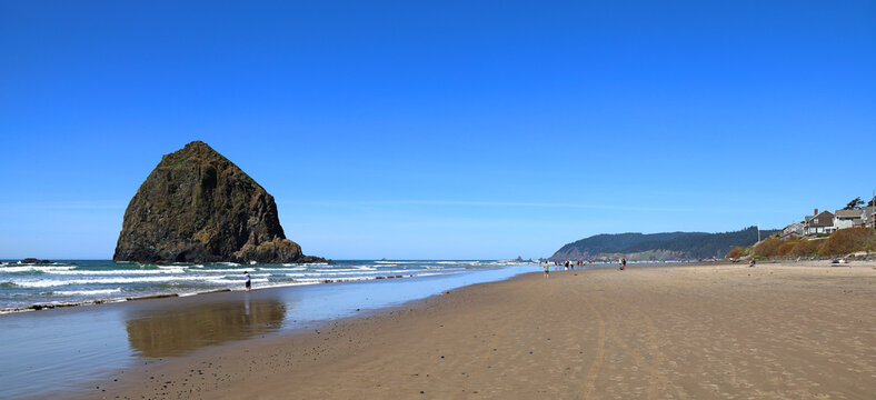 Panoramic view of the iconic Haystack Rock and Cannon Beach in Oregon on a clear sunny day.