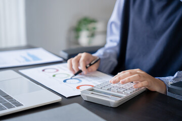 Asian businesswoman doing paper work with pen laptop calculator