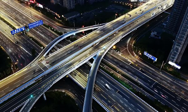 An aerial view of a complex interchange with cars and streetlights, in the evening