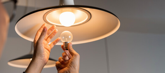 Male hands compare an incandescent light bulb and a LED lamp.