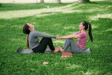 Two Asian beauties doing yoga in a public park.
