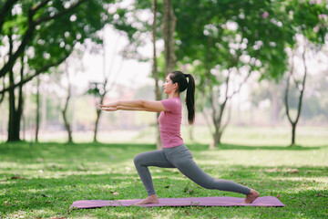 Fototapeta premium Beautiful girl enjoys practicing yoga in the park, warming up for health.