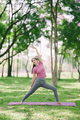 Fototapeta premium Beautiful girl enjoys practicing yoga in the park, warming up for health.