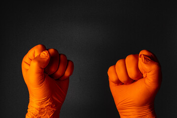 Hands in orange gloves raised in solidarity during protest