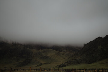 Misty hills behind a wooden fence