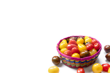 Bright and colorful assorted cherry tomatoes (yellow pear-shaped, red and black striped) in a vivid basket on the white background. Fresh organic garden produce.