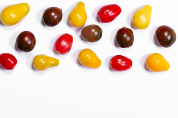 Bright and colorful assorted cherry tomatoes (yellow pear-shaped, red and black striped) on the white background. Fresh organic garden produce.