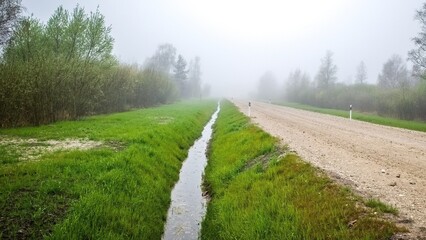 Reclamation ditch along the road. Morning fog.