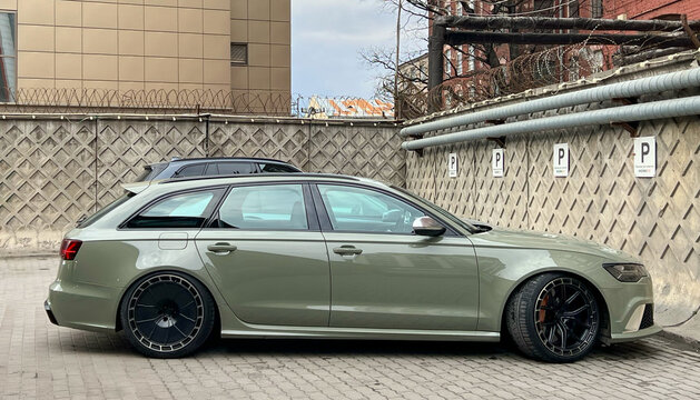A green Audi RS6 touring cars are parked on street, luxury car exterior. The modern exterior of a premium Germany car Audi RS6 Avant (C7) pistachio color. 