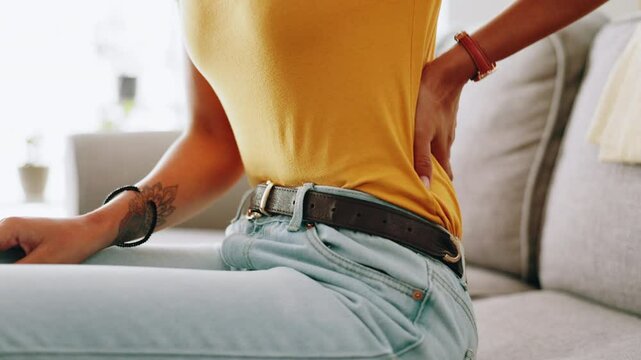 Home, hands and woman on sofa, back pain and inflammation with discomfort. Closeup, apartment and person on couch, bruise and ache with muscle tension, burnout and bad posture in living room