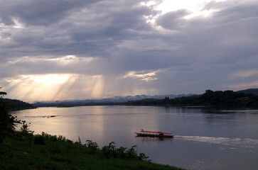 Golden sunset shines down on the river, reflecting in the colorful sky, boats laying fishing buoys in the evening, country life