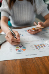 Naklejka premium Close-up of a woman reviewing financial charts and graphs, highlighting business analysis and strategic planning.