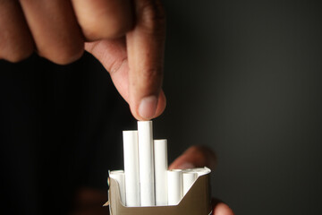 Person placing white tubes into a container in a dimly lit setting