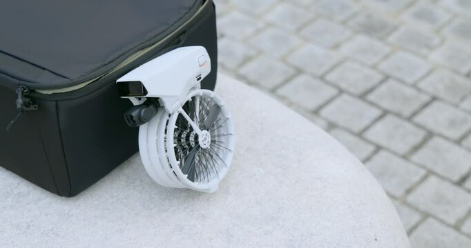 A small drone resting on a bag, showcasing its compact design and functionality, ready for flight. Portability and versatility of this modern drone technology.