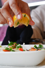 Fresh lemon being squeezed over a vibrant salad at a cafe