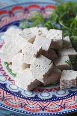 Cubes of soft tofu served on a decorative plate with greenery