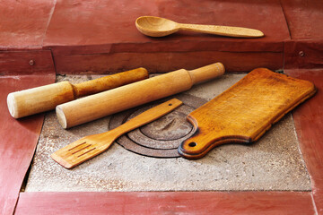 Wooden kitchen utensils on the stove. Wooden cutting board, rolling pins, spoons.