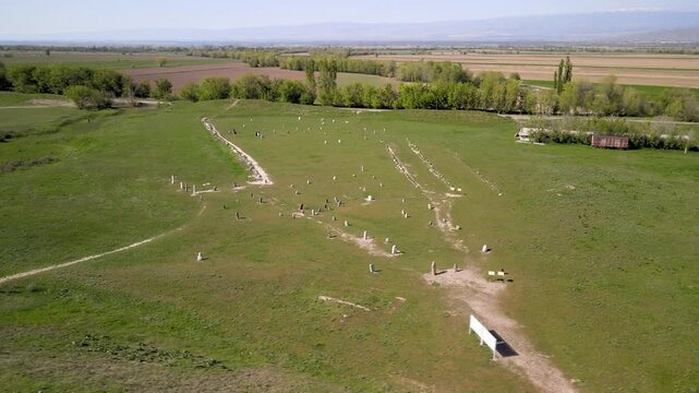 Ancient Stone Statues near Burana Tower, Kyrgyzstan. Aerial view of the collection of stone statues (balbals), scattered across the grassy field.