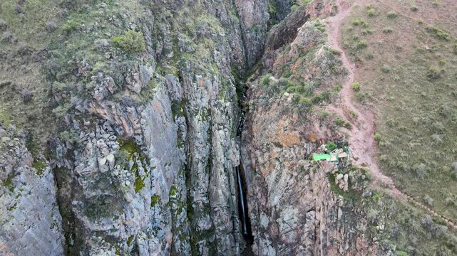 Aerial view of a waterfall cascading down the cliffs neath the Sky Bridge in Chunkurchak Gorge, Kyrgyzstan.